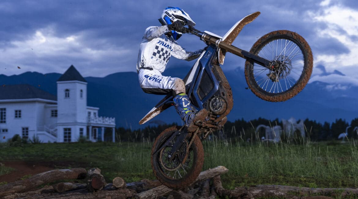 Rider lifting the front wheel of an electric dirt bike over a log